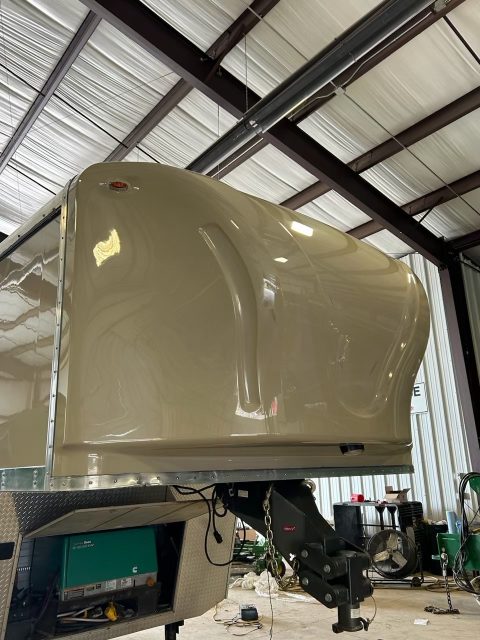 Fifth wheel front cap with a multi-year ceramic coating reflecting the shop lights overhead