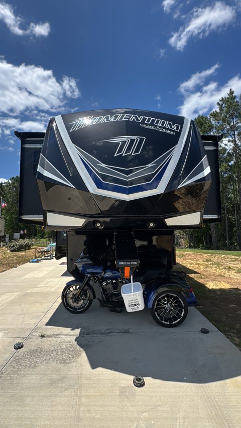 Ceramic-coated Grand Design Momentum toy hauler front cap with the motorcycle it hauls parked beneath