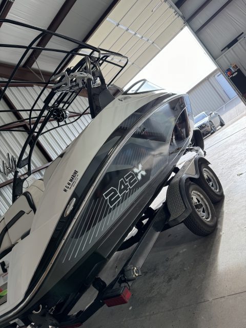 Bow of a detailed Yamaha 242X jet boat reflecting the shop lights along its gelcoat