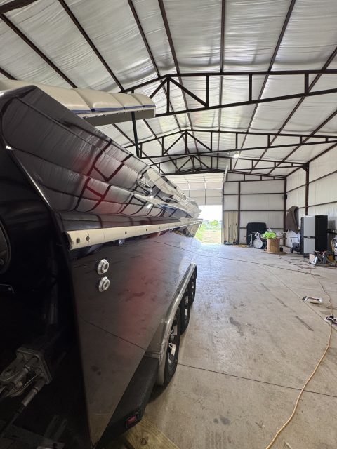 Deep cherry hull of a runabout throwing a mirror reflection down the side of the shop