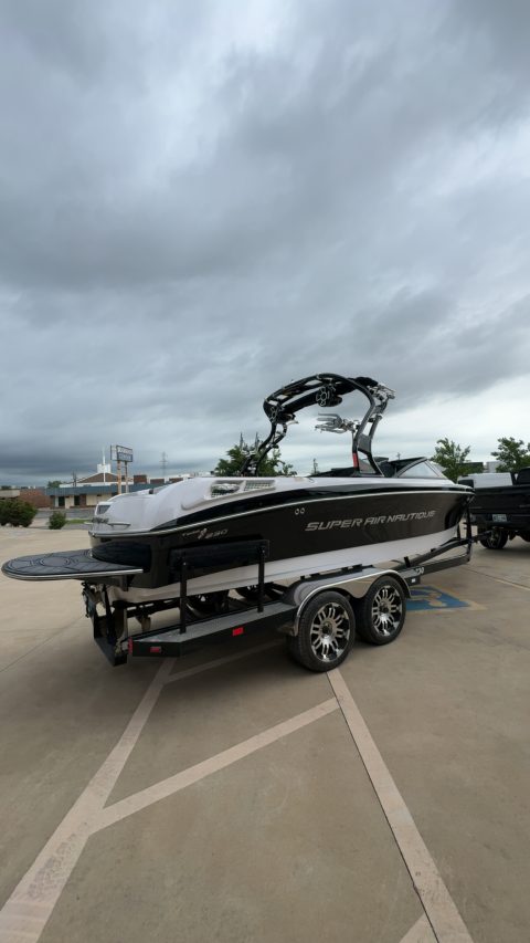 Black and white Super Air Nautique 230 on its trailer under a breaking storm sky